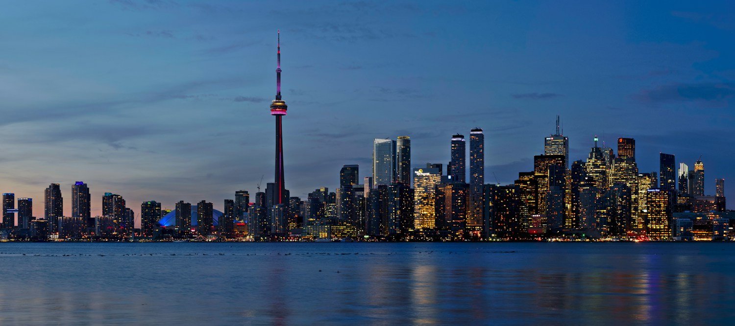 Toronto skyline and the CN Tower reflected in Lake Ontario at dusk.