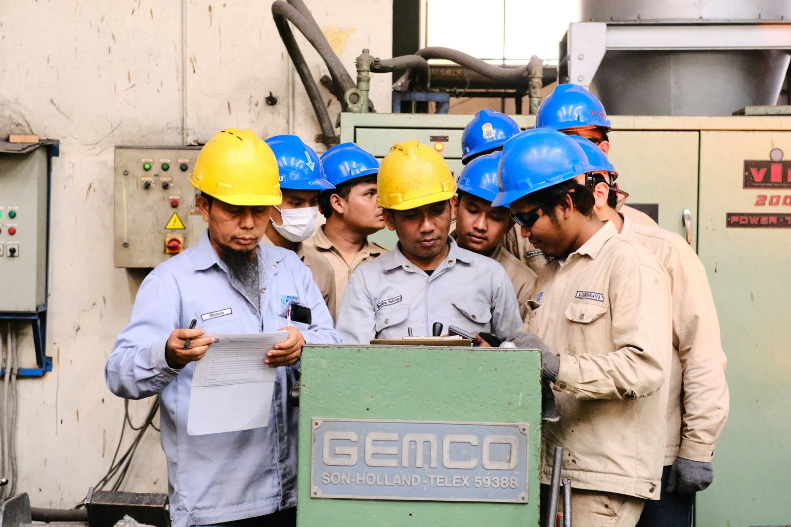 Industrial workers in hard hats reviewing technical documents